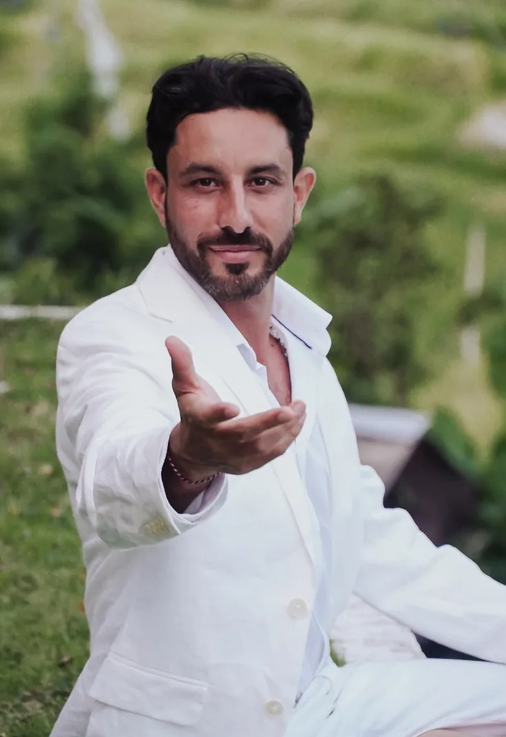 Lukaijah in white linen reaching one open hand toward you, an invitation